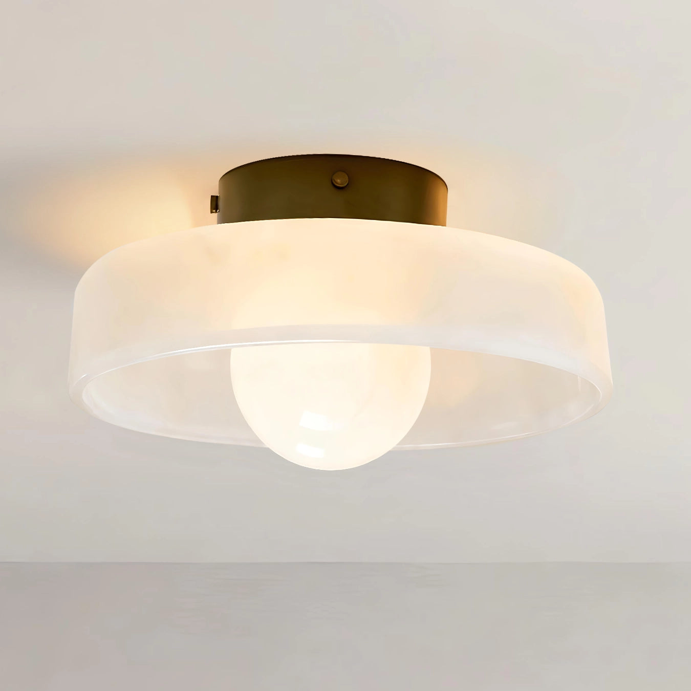Ceiling light fixture with white glass shade and gold metal fixture on a plain background