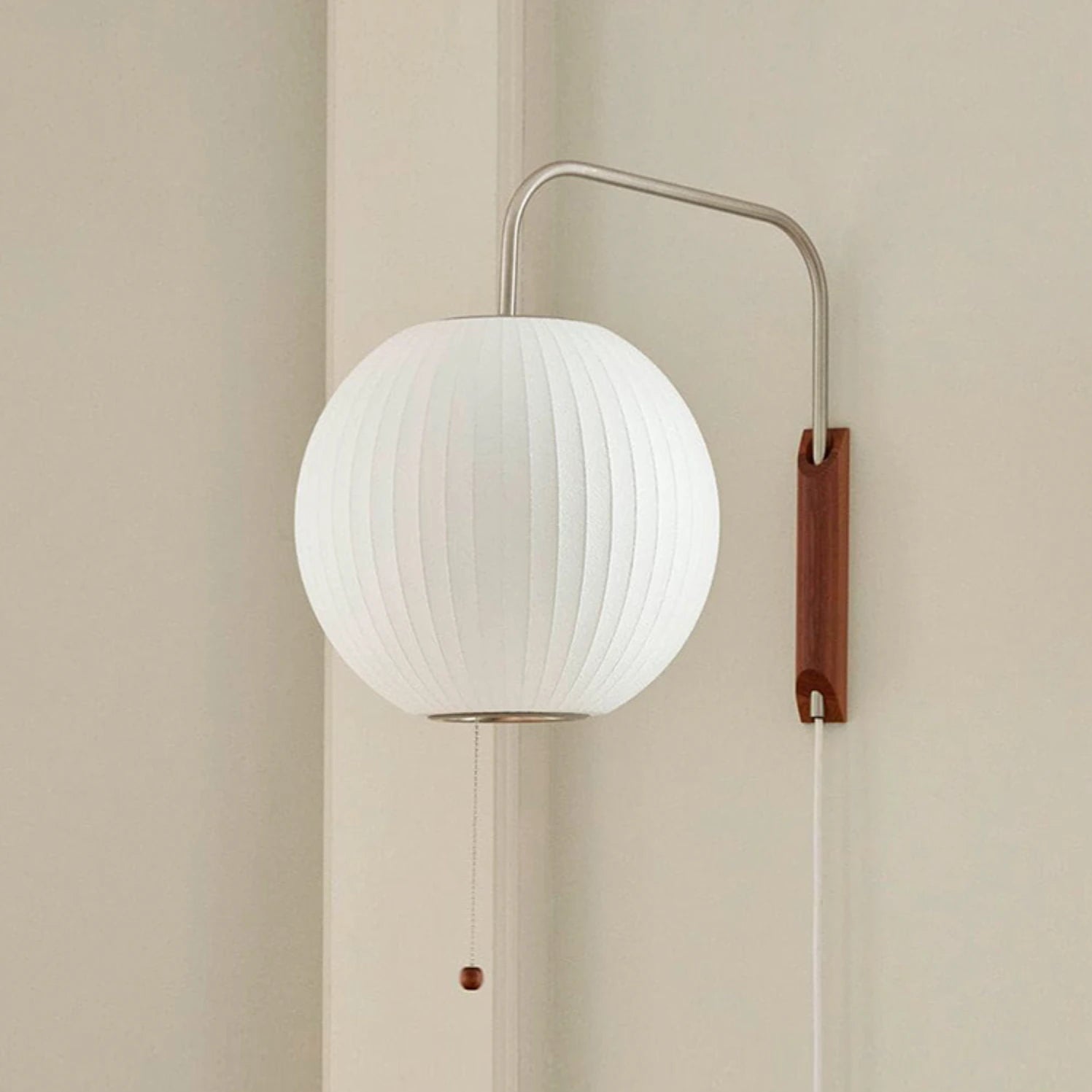 A wall-mounted lamp with a silk shade and a wooden and metal base, featuring a pull string switch.