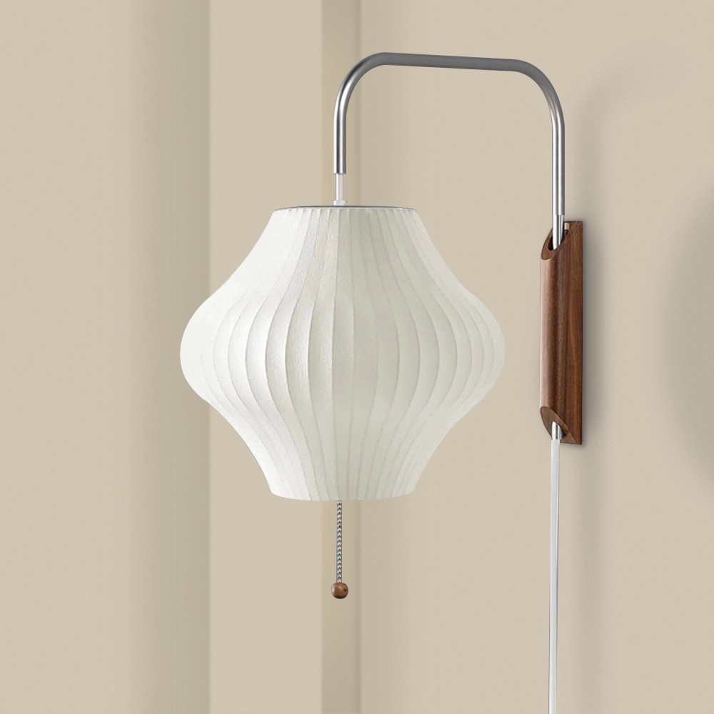 A wall-mounted lamp with a silk shade and a wooden and metal base, featuring a pull string switch.