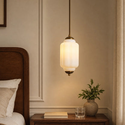 White milk glass pendant light fixture on a wall above a wooden nightstand with a plant