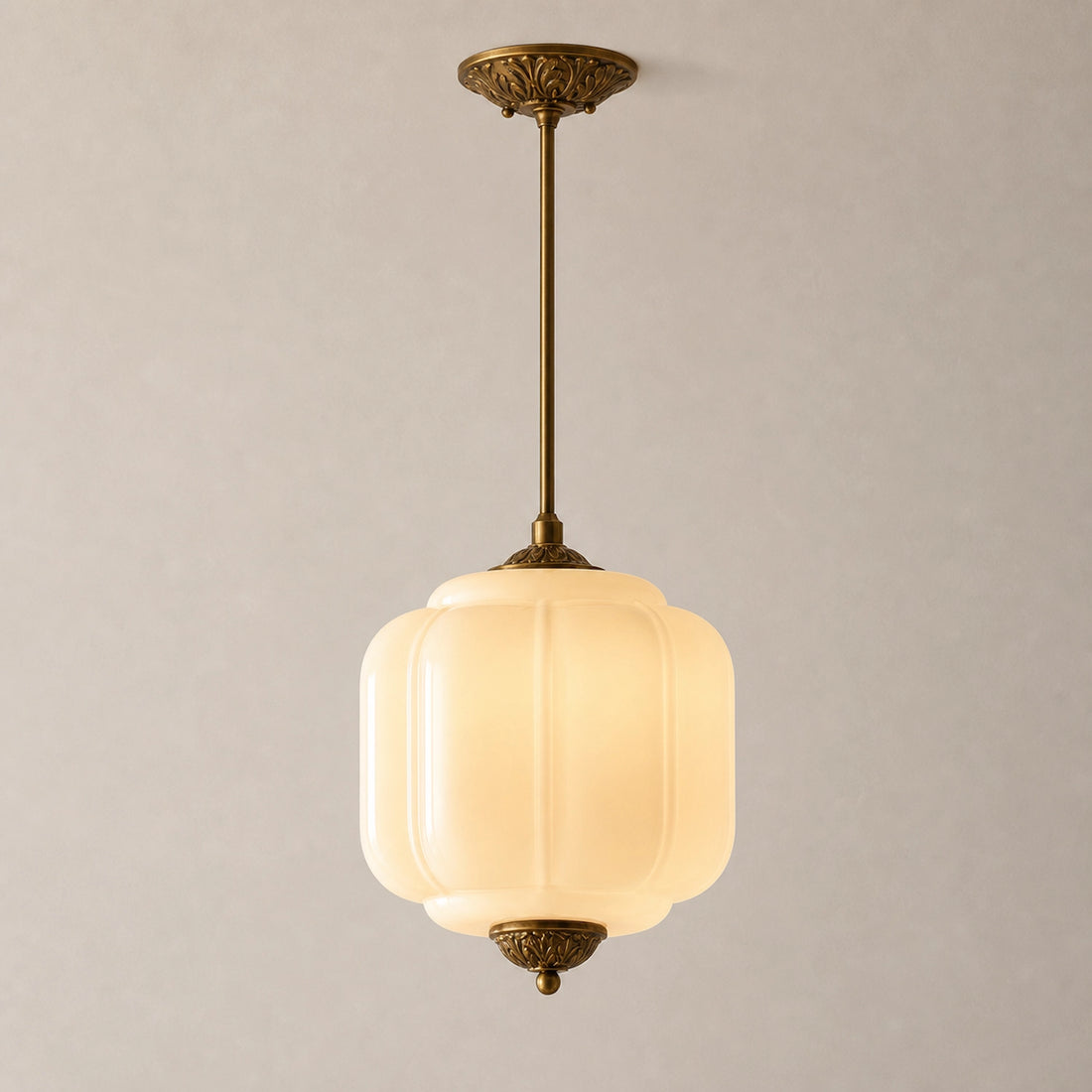 Vintage-style pendant light with white milk glass shade and brass fixture on a neutral background