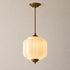 Vintage-style pendant light with white milk glass shade and brass fixture on a neutral background