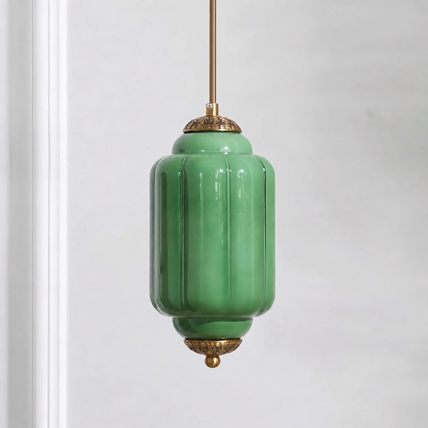 Green milk glass pendant light with brass base on a white background