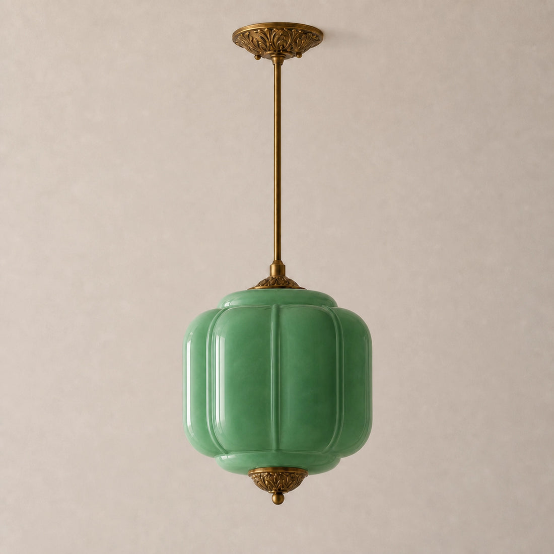 Green milk glass pendant light with brass base on a beige background