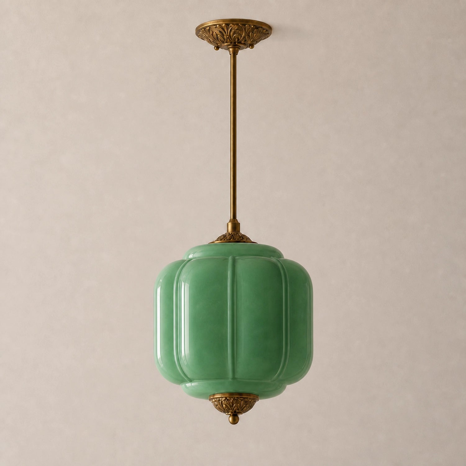 Green milk glass pendant light with brass base on a beige background