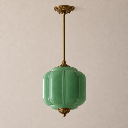 Green milk glass pendant light with brass base on a beige background