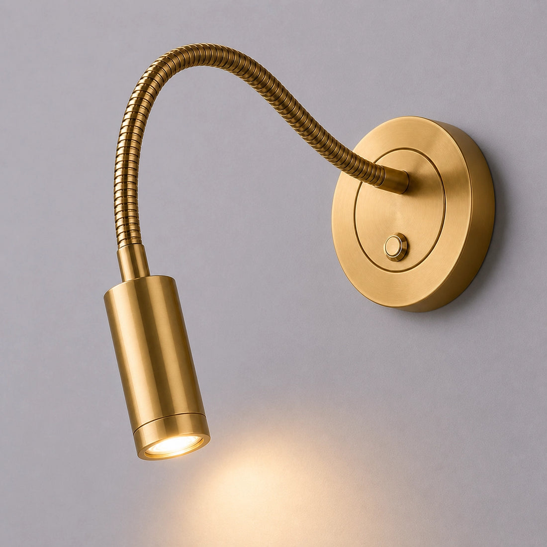 Gold wall-mounted reading light with flexible arm on a gray background