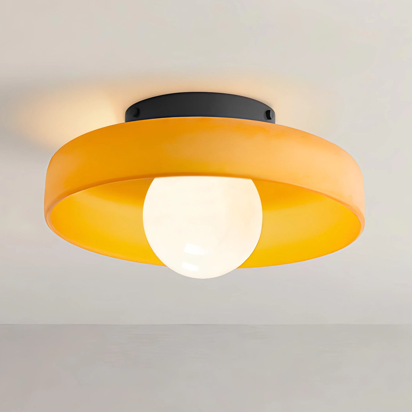 Ceiling light fixture with orange shade and black fixture on a plain background