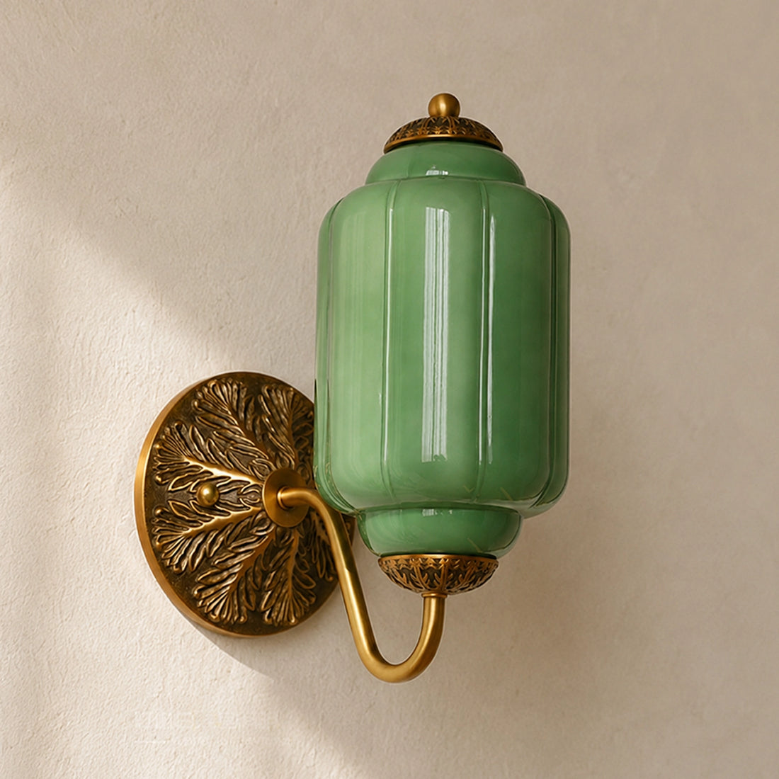 Green eloise glass wall sconce with gold fixture on a beige wall