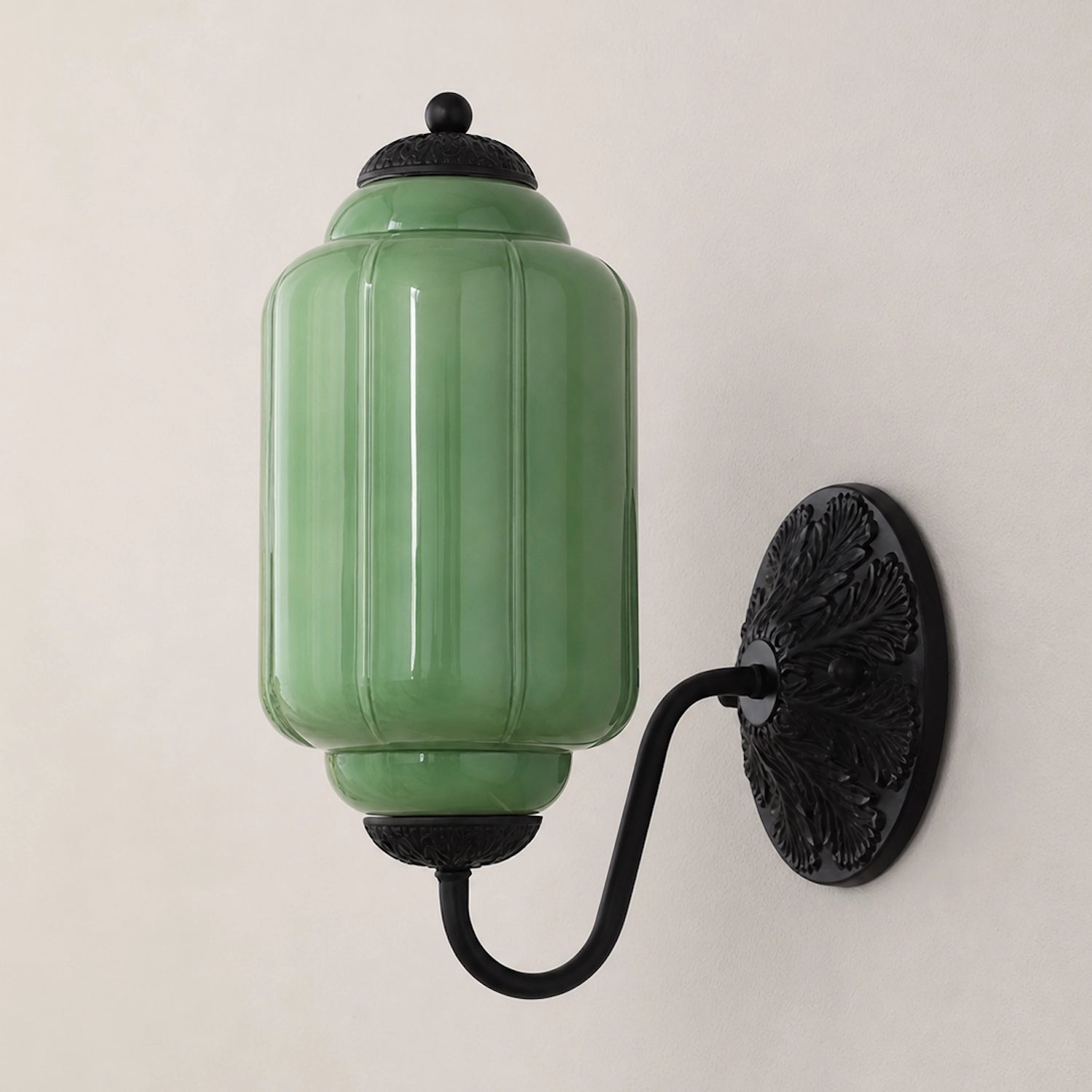 Green eloise glass wall-mounted lamp with black fixture on a light gray background